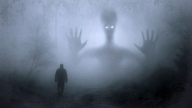 Spooky image with man in foreground and large spirit like creature in the fog